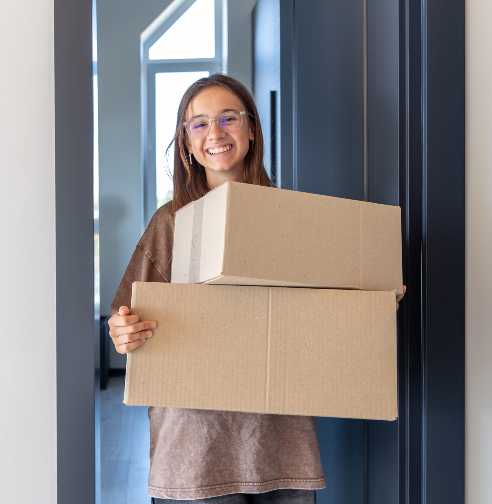 girl walks in with boxes, big step and bright grin. moving day.